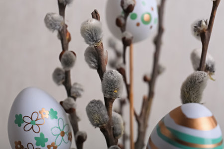 Beautiful willow branches with painted eggs on light gray background, closeup. Easter decorの写真素材