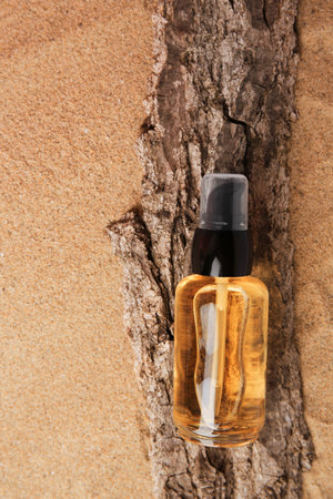 Bottle of serum and tree bark on sand, top viewの写真素材