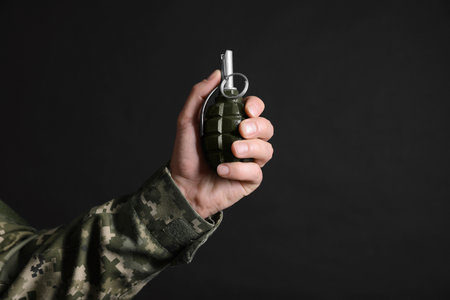 Soldier holding hand grenade on black background, closeup with space for text. Military serviceの写真素材
