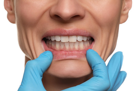 Doctor examining woman's gums on white background, closeup