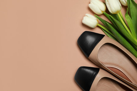 Pair of new stylish square toe ballet flats and beautiful tulips on beige background, flat lay. Space for textの写真素材