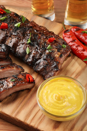 Tasty grilled ribs and sauce on wooden table, closeupの写真素材