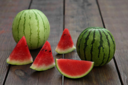 Different delicious ripe watermelons on wooden tableの写真素材