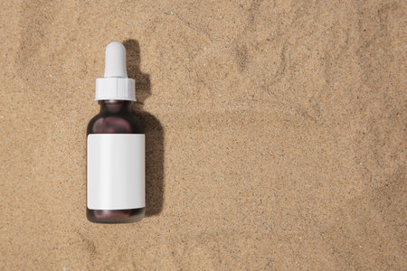 Bottle with serum on sand, top view and space for text. Cosmetic productの写真素材