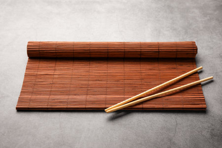 Rolled bamboo mat and chopsticks on gray tableの写真素材