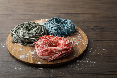 Rolled pasta painted with food colorings and flour on wooden tableの写真素材