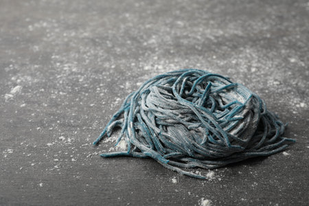 Rolled spaghetti painted with food coloring and flour on dark gray table, closeup. Space for textの写真素材