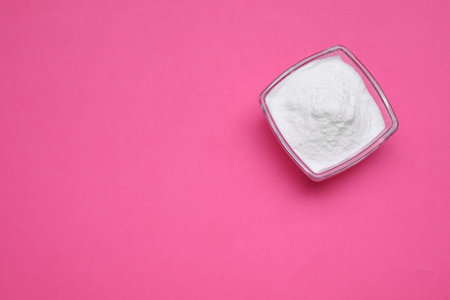 Bowl of sweet powdered fructose on pink background, top view. Space for textの写真素材