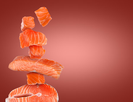 Cut fresh salmon falling on dark red gradient background, space for textの写真素材