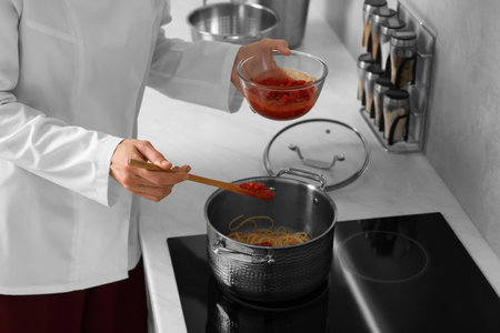 Professional chef cooking delicious pasta in saucepan indoors, closeupの写真素材