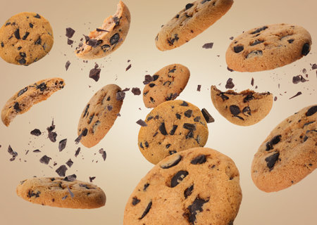 Tasty chocolate chip cookies falling on pale light brown backgroundの写真素材