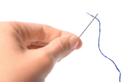 Woman holding sewing needle with thread on white background, closeup