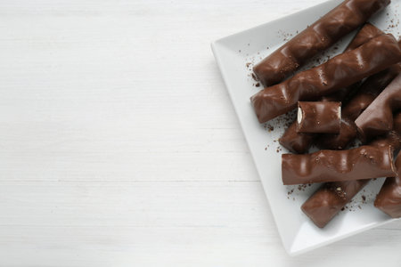 Tasty chocolate bars on white wooden table, top view. Space for text
