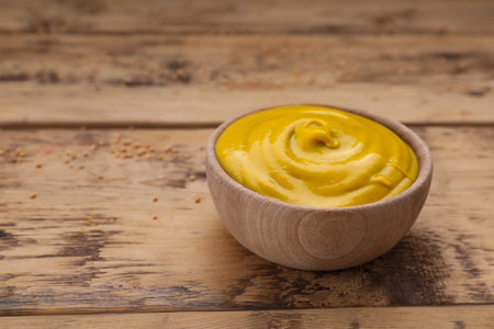 Sauce bowl with delicious mustard on wooden table. Space for textの写真素材
