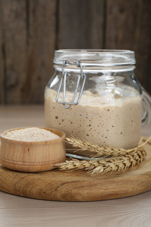 Leaven and ears of wheat on beige wooden tableの写真素材