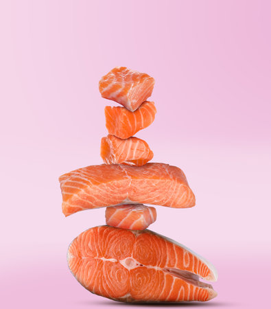 Cut fresh salmon falling on pink gradient backgroundの写真素材