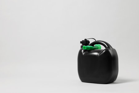 Black plastic canister with nozzle on light gray background. Space for textの写真素材