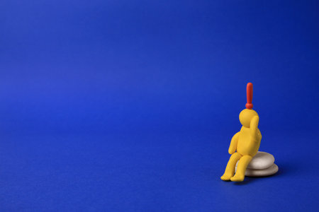 Human figure made of yellow plasticine with exclamation mark as solution idea on blue background. Space for textの写真素材