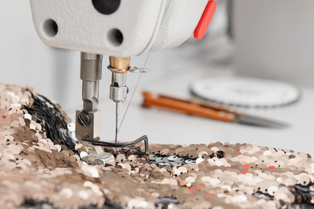Sewing machine and beautiful fabric with paillettes indoors, closeup