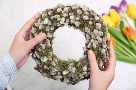 Woman holding wreath made of beautiful willow branches on blurred background, closeupの写真素材