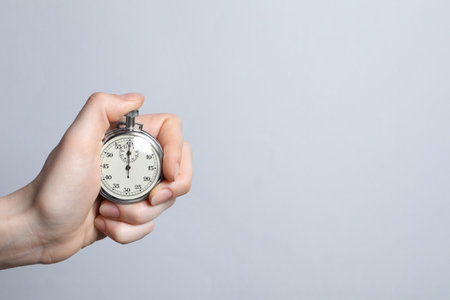 Woman holding vintage timer on light gray background, closeup. Space for textの写真素材