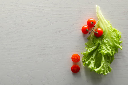 Food photography. Fresh cherry tomatoes and lettuce on white wooden table, flat lay with space for textの写真素材