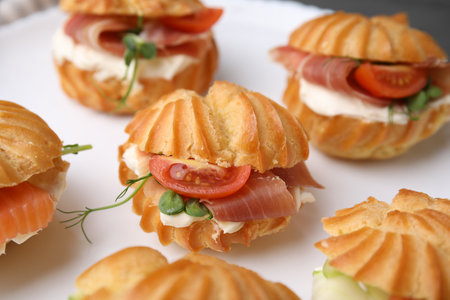 Delicious profiteroles with tasty filling on plate, closeup view