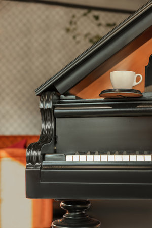Cup with coaster on black grand piano in cafeの写真素材