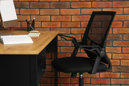Comfortable office chair near desk at workplaceの写真素材