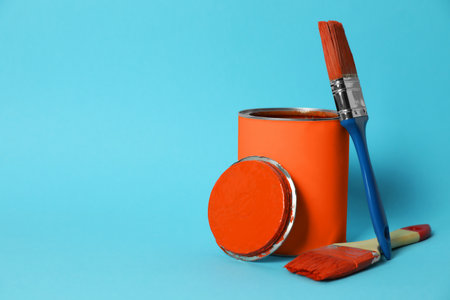 Can of orange paint and brushes on turquoise background. Space for textの写真素材