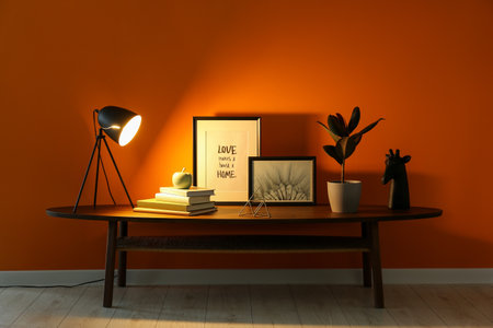 Wooden coffee table with different decor near orange wall indoors. Stylish interior designの写真素材
