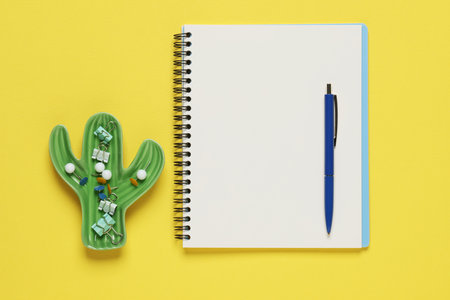 Ballpoint pen, notebook and different clips on yellow background, flat layの写真素材