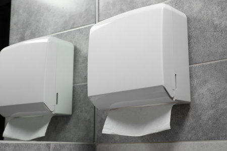 New paper towel dispenser hanging on wall near mirror in bathroomの写真素材