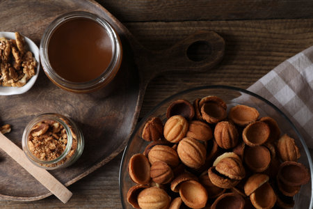 Making walnut shaped cookies. Cooked dough, caramelized condensed milk and nuts on wooden table, flat layの写真素材