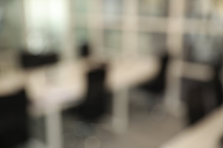 Blurred view of cozy workspaces with tables and chairs in officeの写真素材