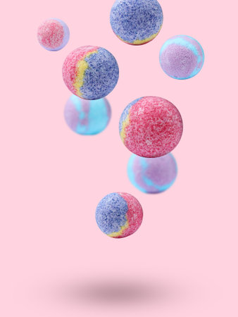 Many different bath bombs falling on pastel pink backgroundの写真素材