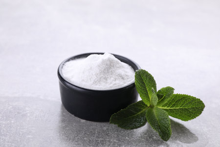 Sweet fructose powder and mint leaves on light gray table