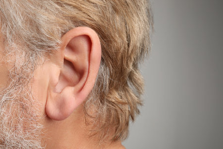 Closeup view of man against light gray background, focus on ear