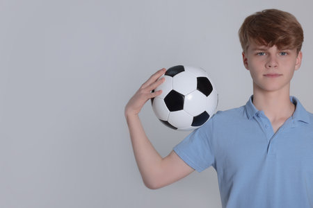 Teenage boy with soccer ball on light gray background. Space for textの写真素材