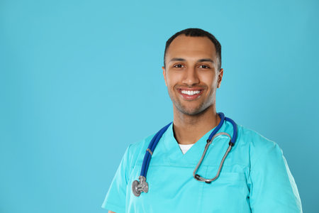 Doctor or medical assistant (male nurse) with stethoscope on turquoise background. Space for textの写真素材