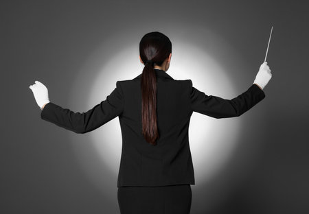 Professional conductor with baton on gray background, back viewの写真素材