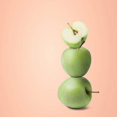 Stack of fresh ripe green apples on pink beige background, space for textの写真素材
