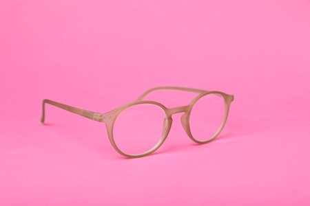 Glasses with corrective lenses on bright pink background