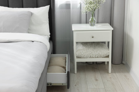 Storage drawer with bedding under comfortable bed in room