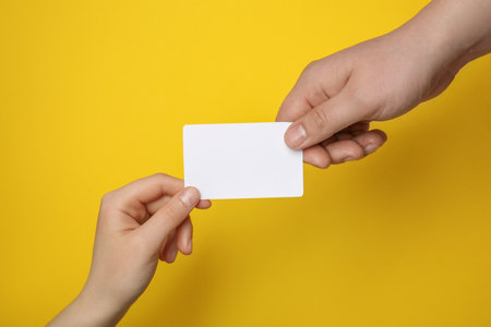 Man and woman holding blank gift card on yellow background, closeupの写真素材