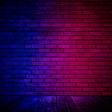 Room with brick wall and wooden floor in neon lightsの写真素材
