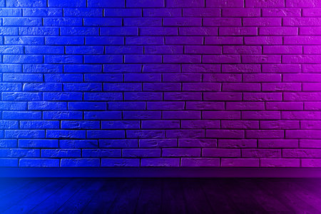 Room with brick wall and wooden floor in neon lightsの写真素材