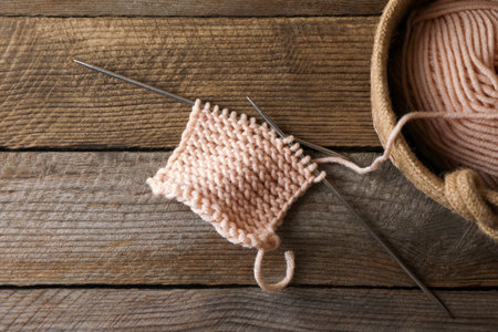 Soft beige yarn, knitting and metal needles on wooden table, flat layの写真素材