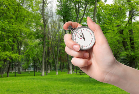 Woman holding timer in park outdoors, closeup. Space for text