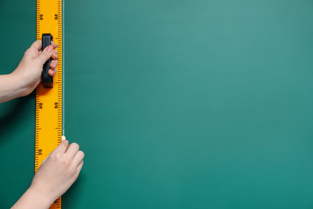 Woman drawing with chalk and ruler on green board, closeup. Space for textの写真素材